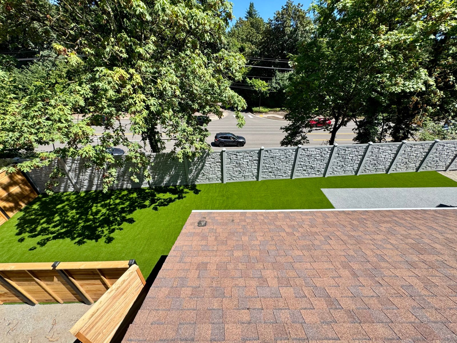 Backyard artificial turf with stacked-stone fence and patio